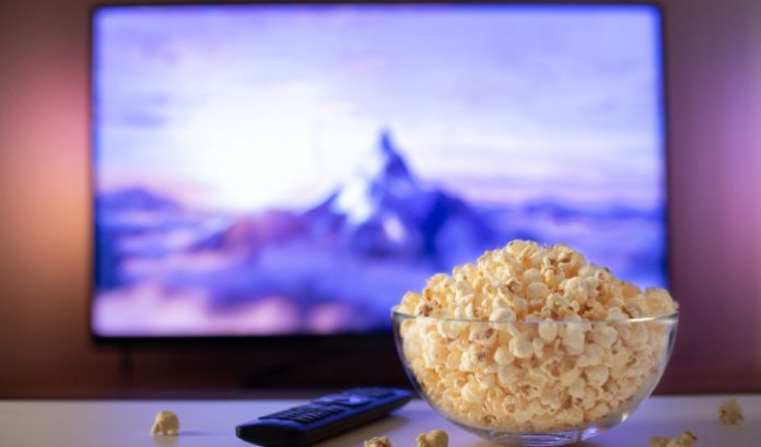 A bowl of popcorn in front of a TV screen