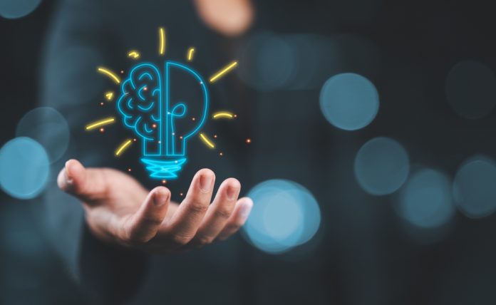 Hand,Holding,Drawing,Virtual,Lightbulb,With,Brain,On,Bokeh,Background Lightbulb denoting innovation