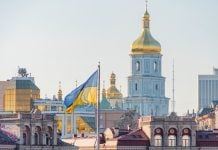 Ukraine publishes official monitoring mechanisms for domestic lotteries Skyline of Kyiv, Ukraine, with Ukrainian flag in foreground