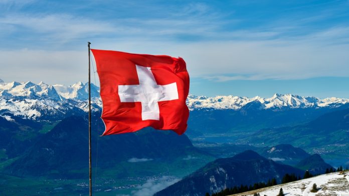 A shot of the Swiss mountains with a Swiss flag in the foreground